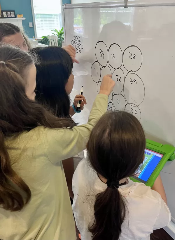 4 female students doing a math problem on a whiteboard