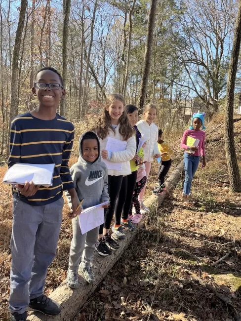 Kids standing on a log in the woods