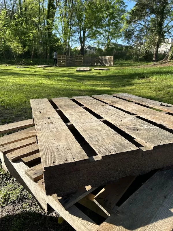 Two pallets in focus with a structure being created in the background